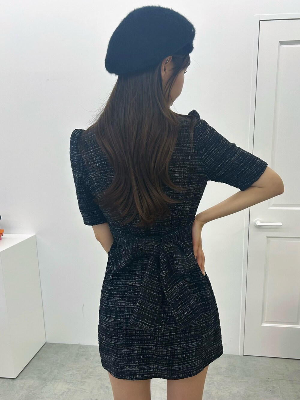 ホワイト系のハンドバッグ、ブラック系のワンピース、ブラック系のパンプスを着用したレディースの夏コーディネートの8枚目の写真