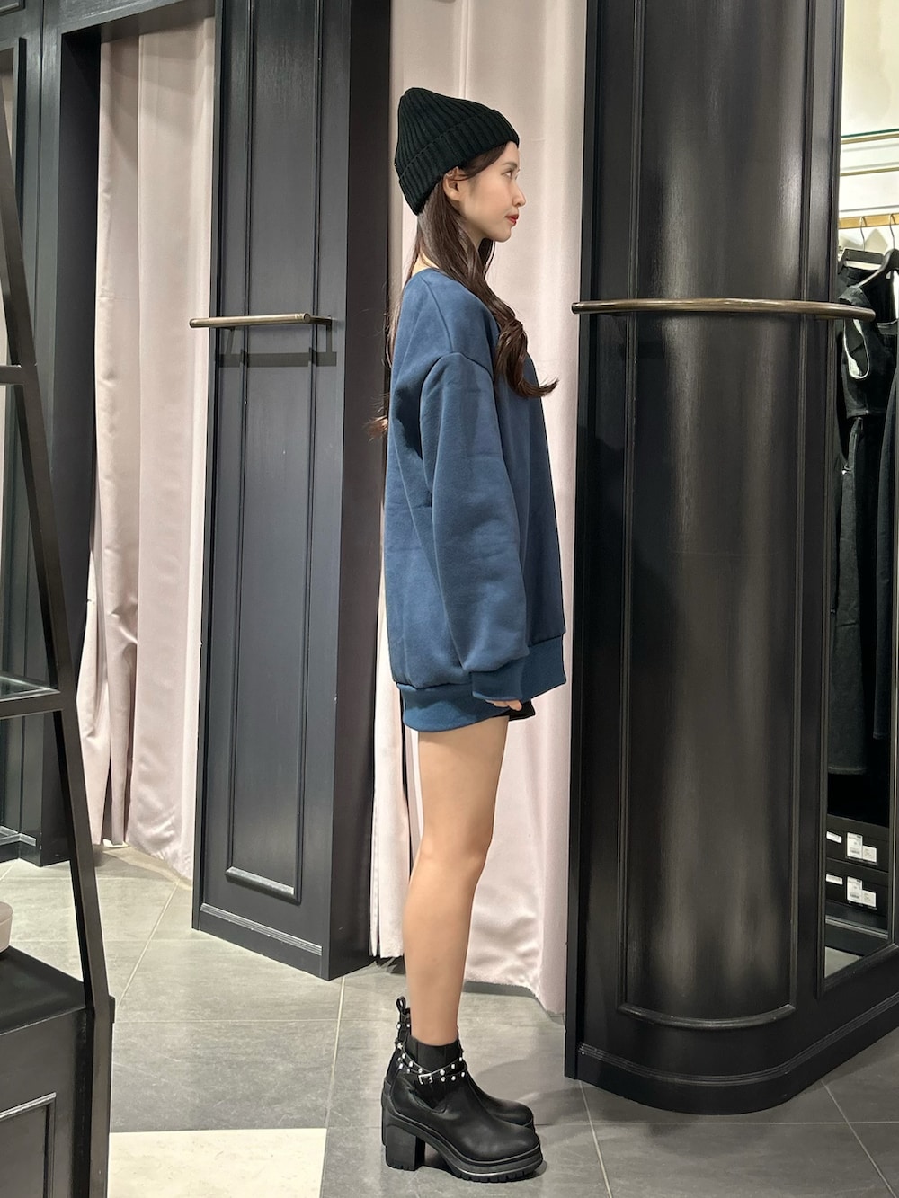 ブルー系のスウェット、ブラック系のブーツ、ブラック系のニットキャップ/ビーニーを着用したレディースの秋コーディネートの2枚目の写真