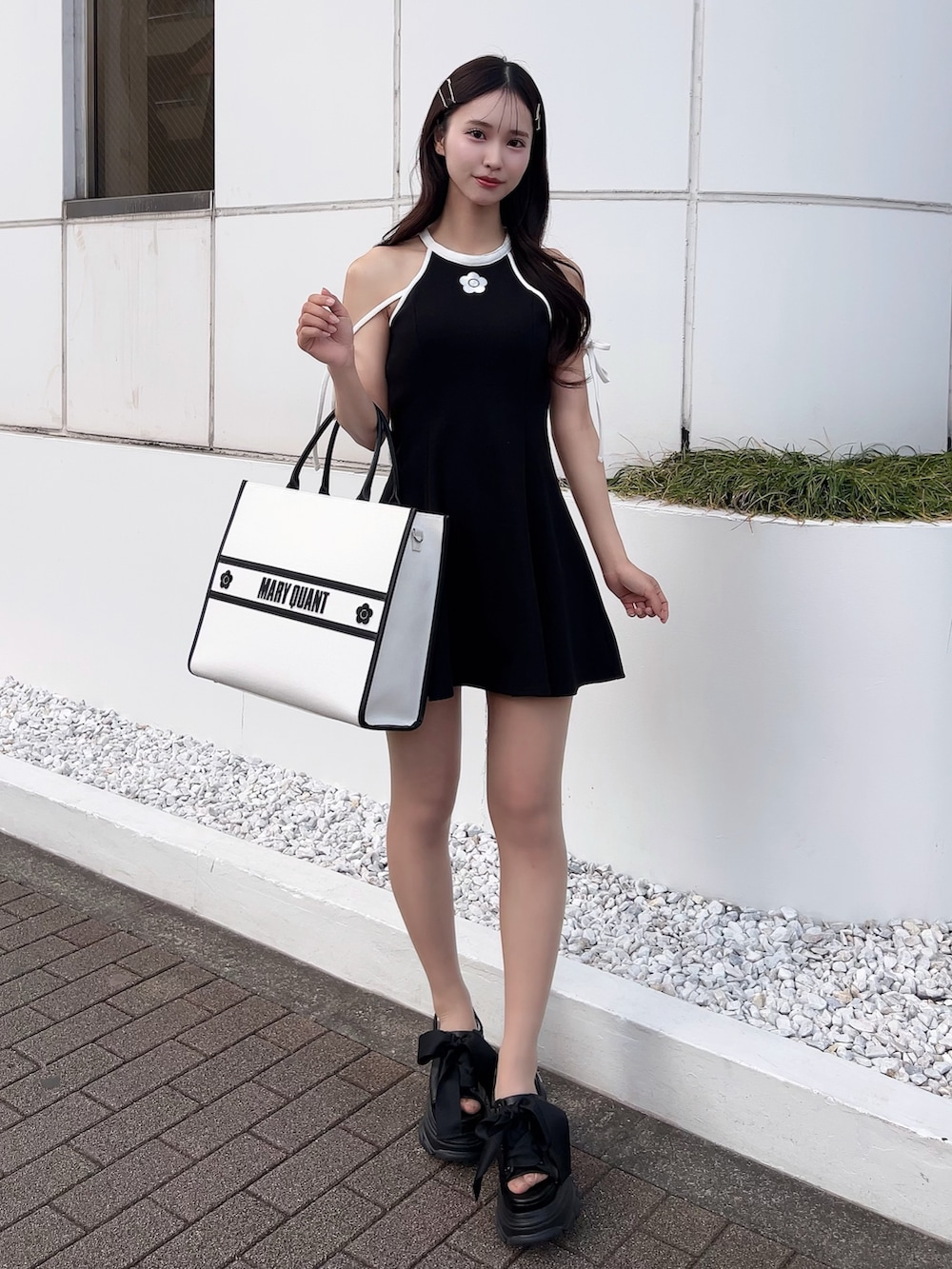 ブラック系のワンピース、ホワイト系のトートバッグ、ブラック系のサンダルを着用したレディースの春コーディネートの2枚目の写真