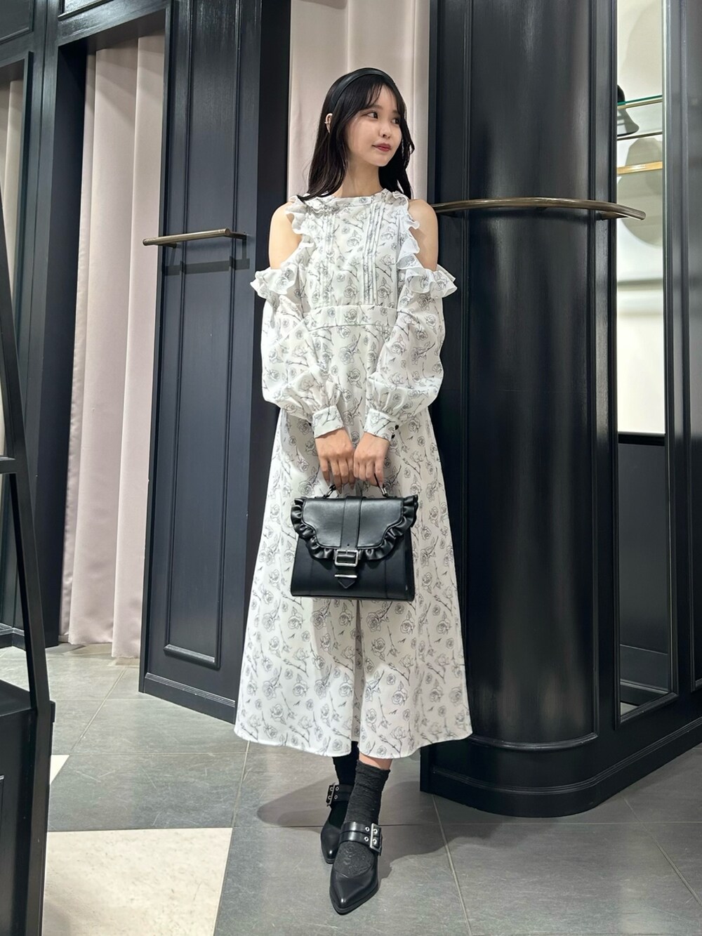 ホワイト系のワンピース、ブラック系のパンプス、ブラック系のショルダーバッグを着用したレディースの冬コーディネートの2枚目の写真