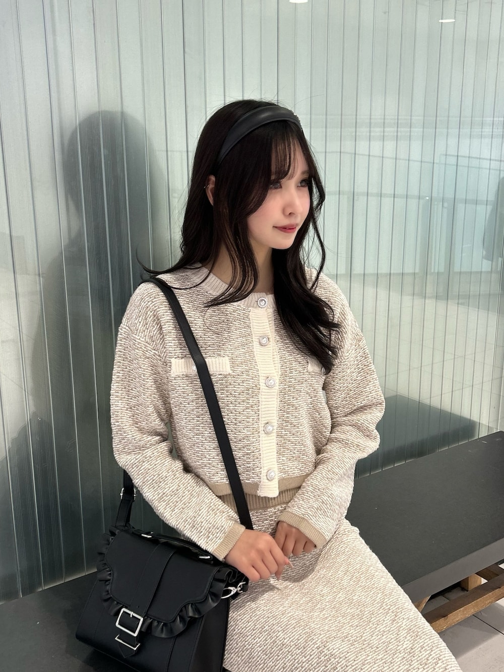 ベージュ系のスカート、ベージュ系のカーディガン/ボレロ、ブラック系のショルダーバッグを着用したレディースの冬コーディネートの2枚目の写真