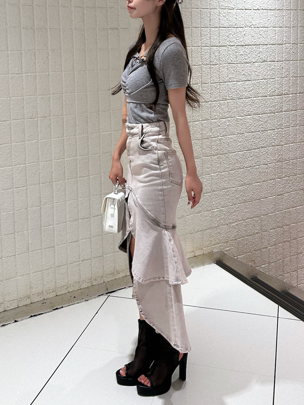 ピンク系のデニムスカート、グレー系のTシャツ/カットソー、ブラック系のサンダルを着用したレディースの秋コーディネートの2枚目の写真