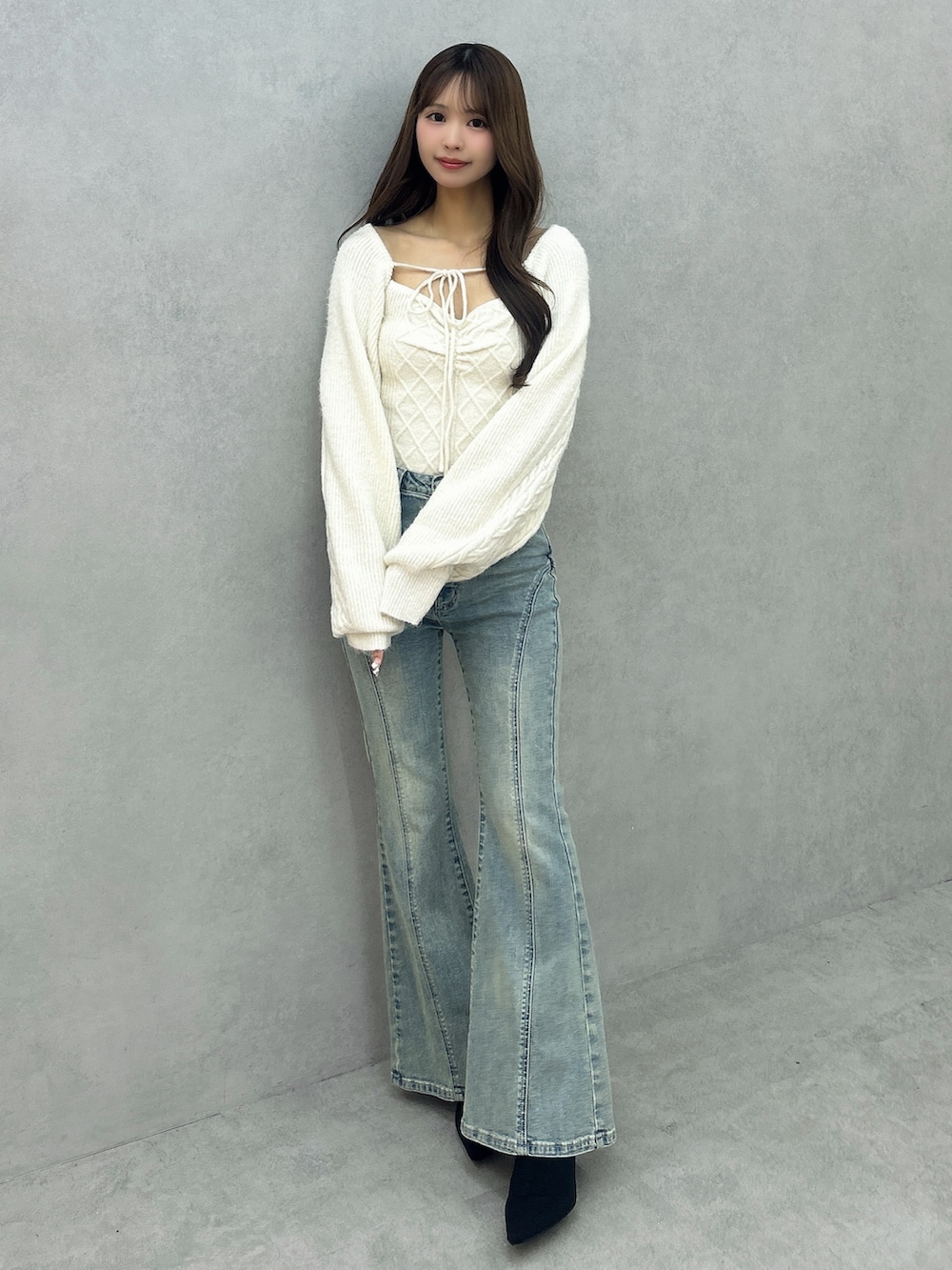 ブルー系のデニムパンツ、ホワイト系のニット/セーター、ブラック系のブーツを着用したレディースの冬コーディネートの2枚目の写真