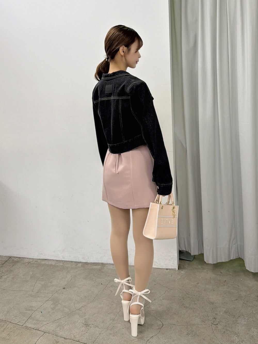 ピンク系のワンピース、ブラック系のデニムジャケット、ホワイト系のサンダルを着用したレディースの春コーディネートの4枚目の写真