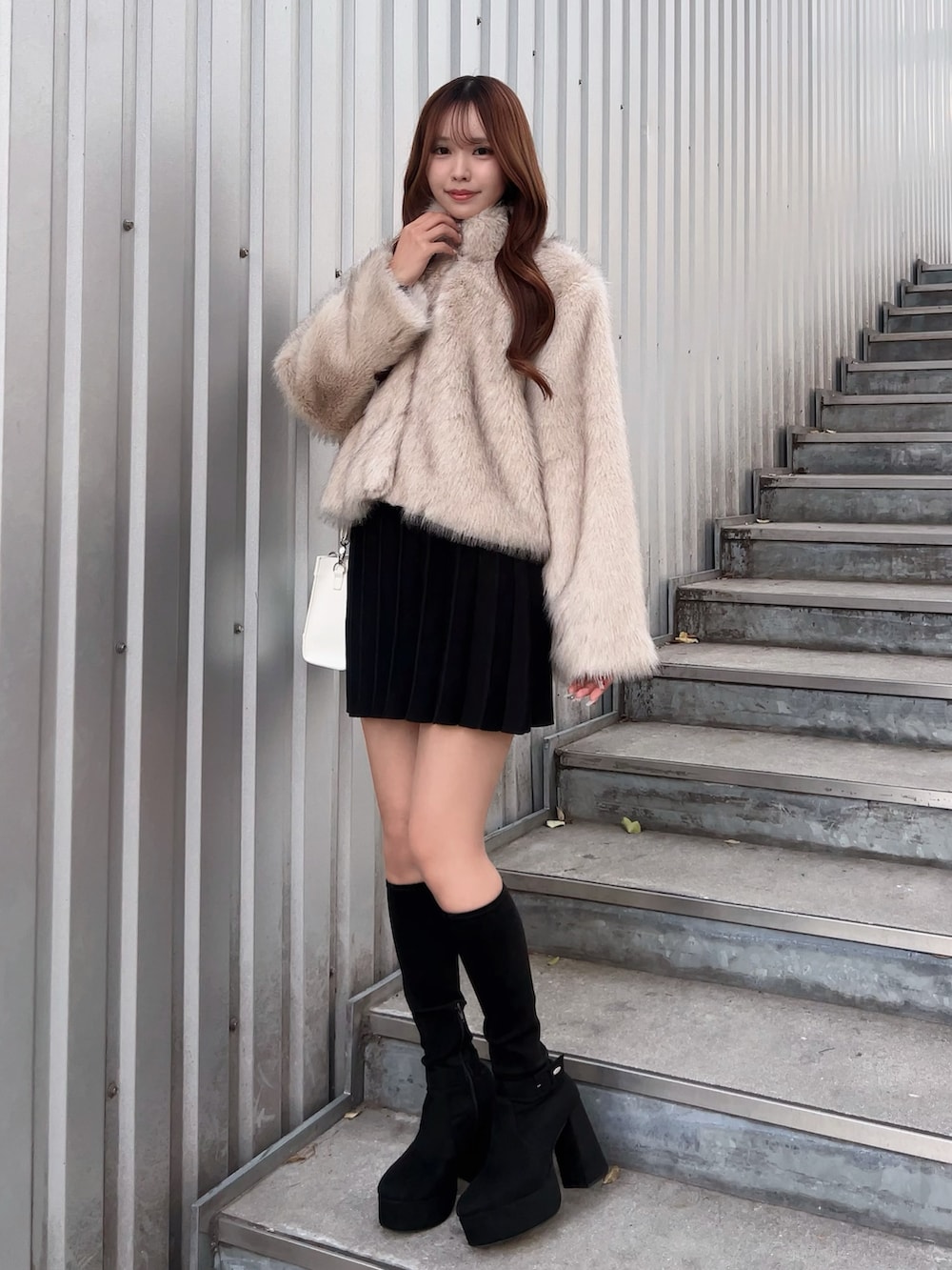 ベージュ系のブルゾン、ブラック系のワンピース、ブラック系のブーツを着用したレディースの冬コーディネートの2枚目の写真