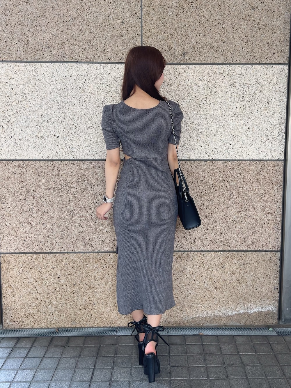 グレー系のワンピース、ブラック系のサンダル、ブラック系のハンドバッグを着用したレディースの春コーディネートの3枚目の写真