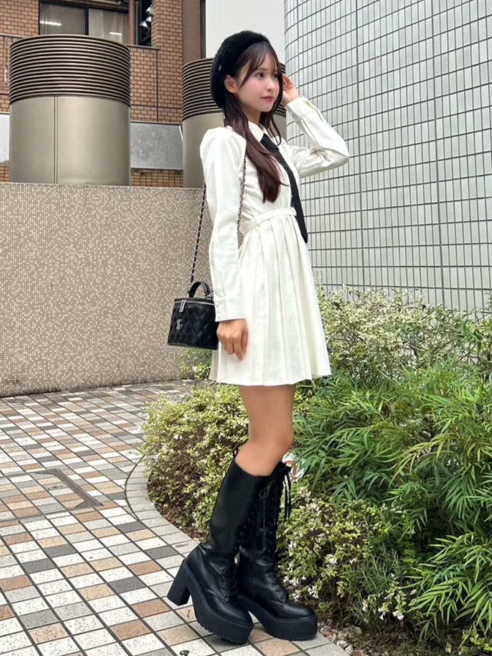 ホワイト系のワンピース、ブラック系のハンドバッグ、ブラック系のブーツを着用したレディースの秋コーディネートの2枚目の写真