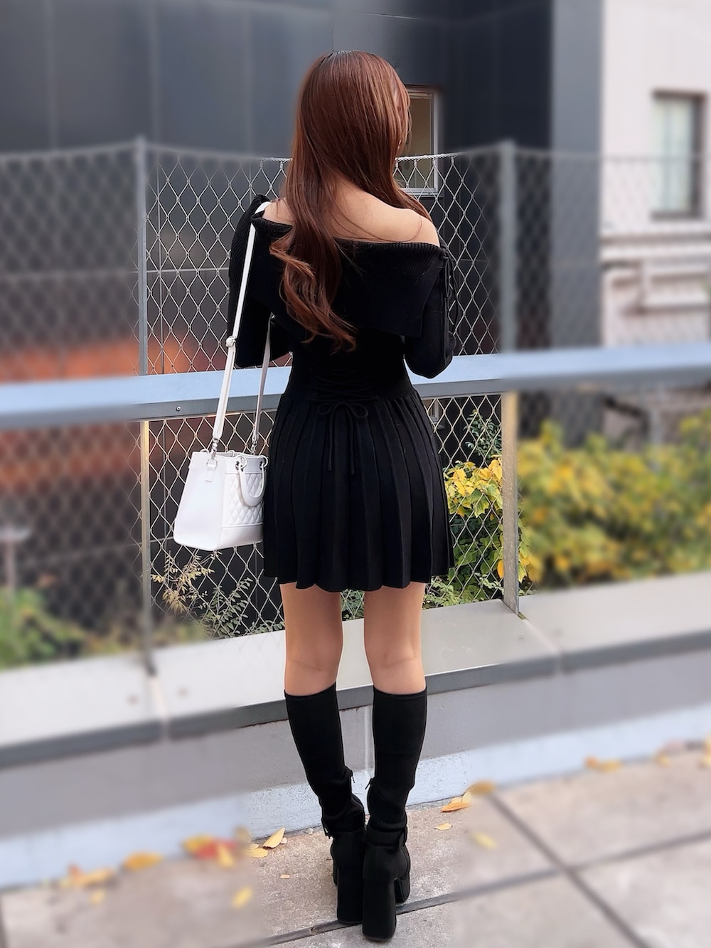 ブラック系のワンピース、ホワイト系のハンドバッグ、ブラック系のブーツを着用したレディースの冬コーディネートの4枚目の写真