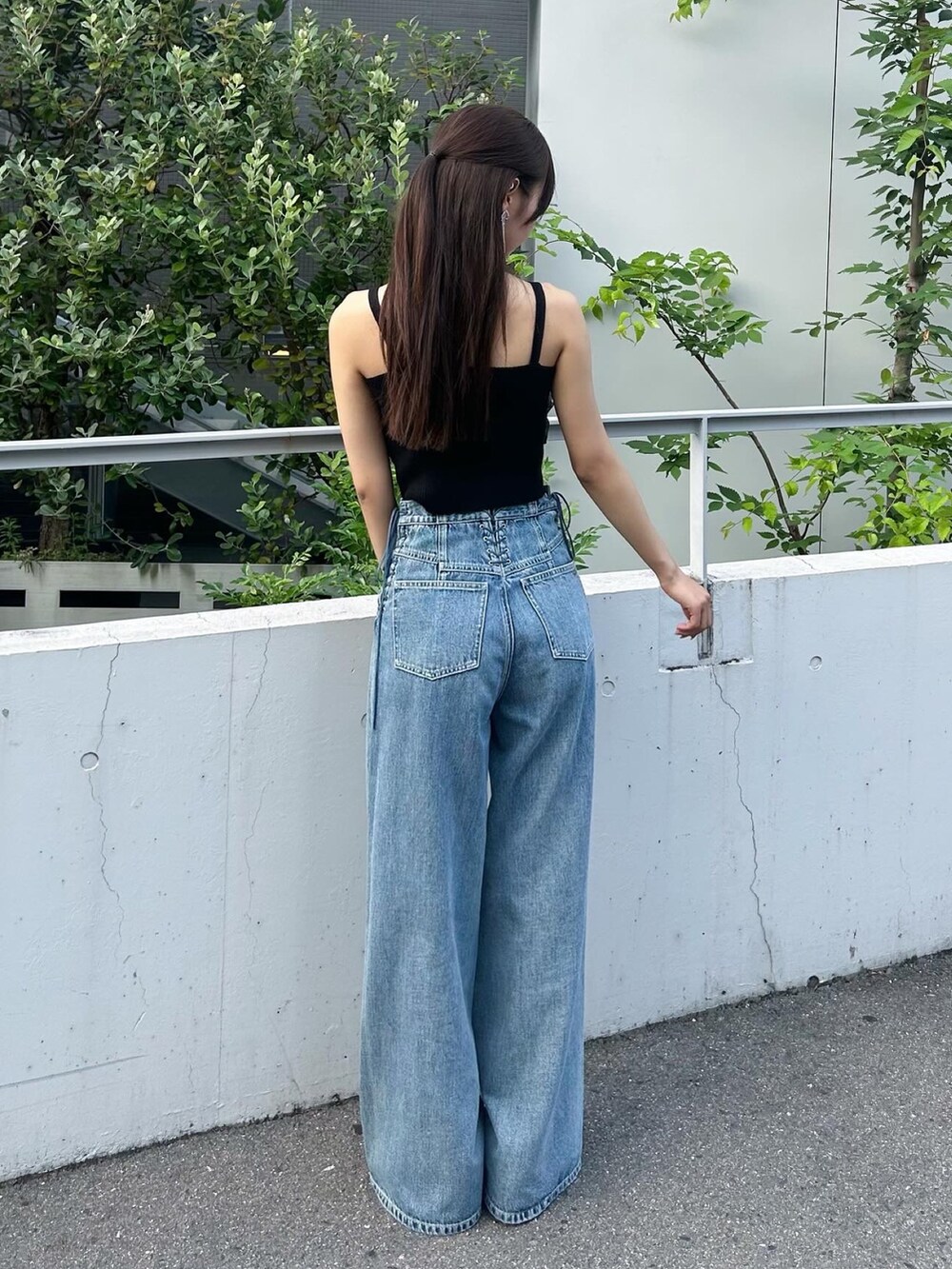 ブラック系のキャミソール、ブルー系のデニムパンツ、ブラック系のパンプスを着用したレディースの夏コーディネートの3枚目の写真