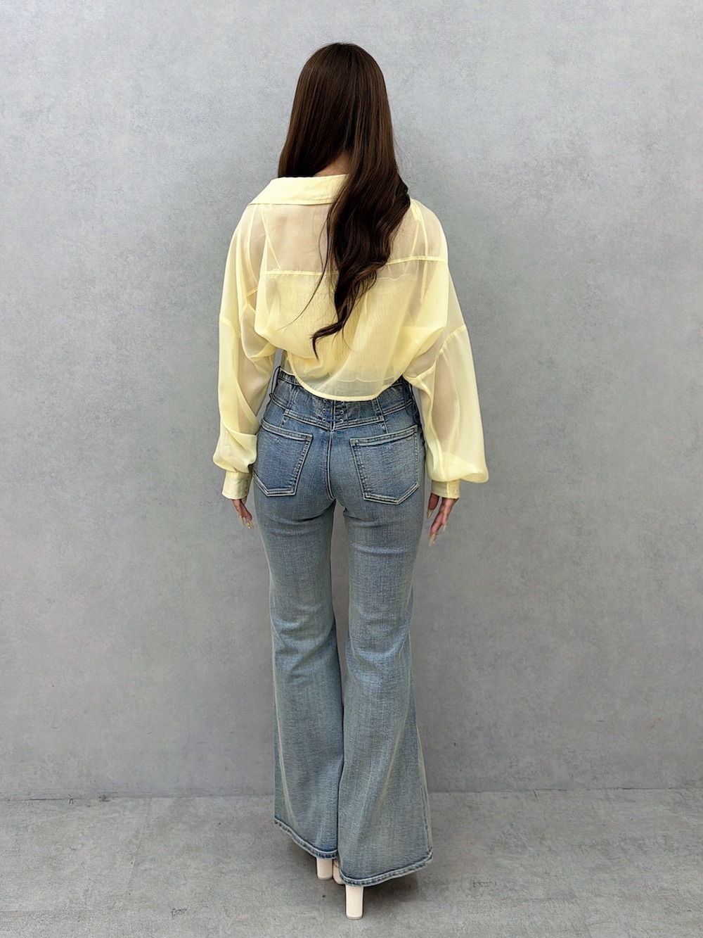 ブルー系のデニムパンツ、イエロー系のシャツ/ブラウス、ホワイト系のサンダルを着用したレディースの春コーディネートの4枚目の写真