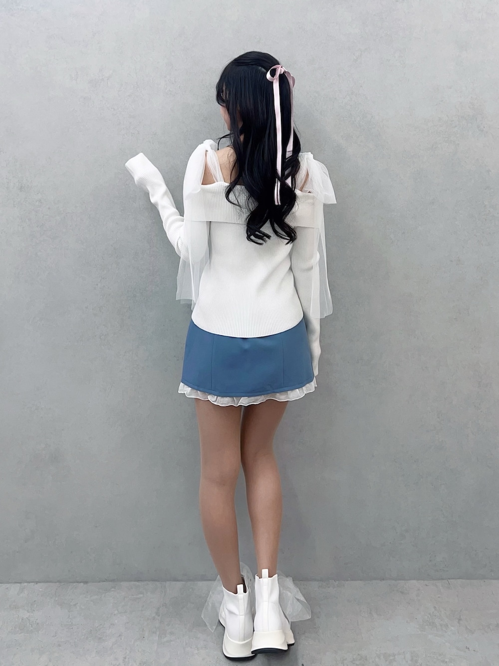 ホワイト系のニット/セーター、ブルー系のスカート、ホワイト系のブーツを着用したレディースの冬コーディネートの4枚目の写真