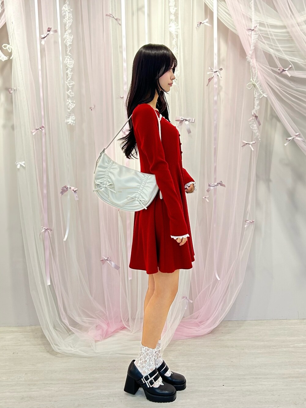 レッド系のワンピース、ホワイト系のショルダーバッグ、ブラック系のパンプスを着用したレディースの冬コーディネートの2枚目の写真