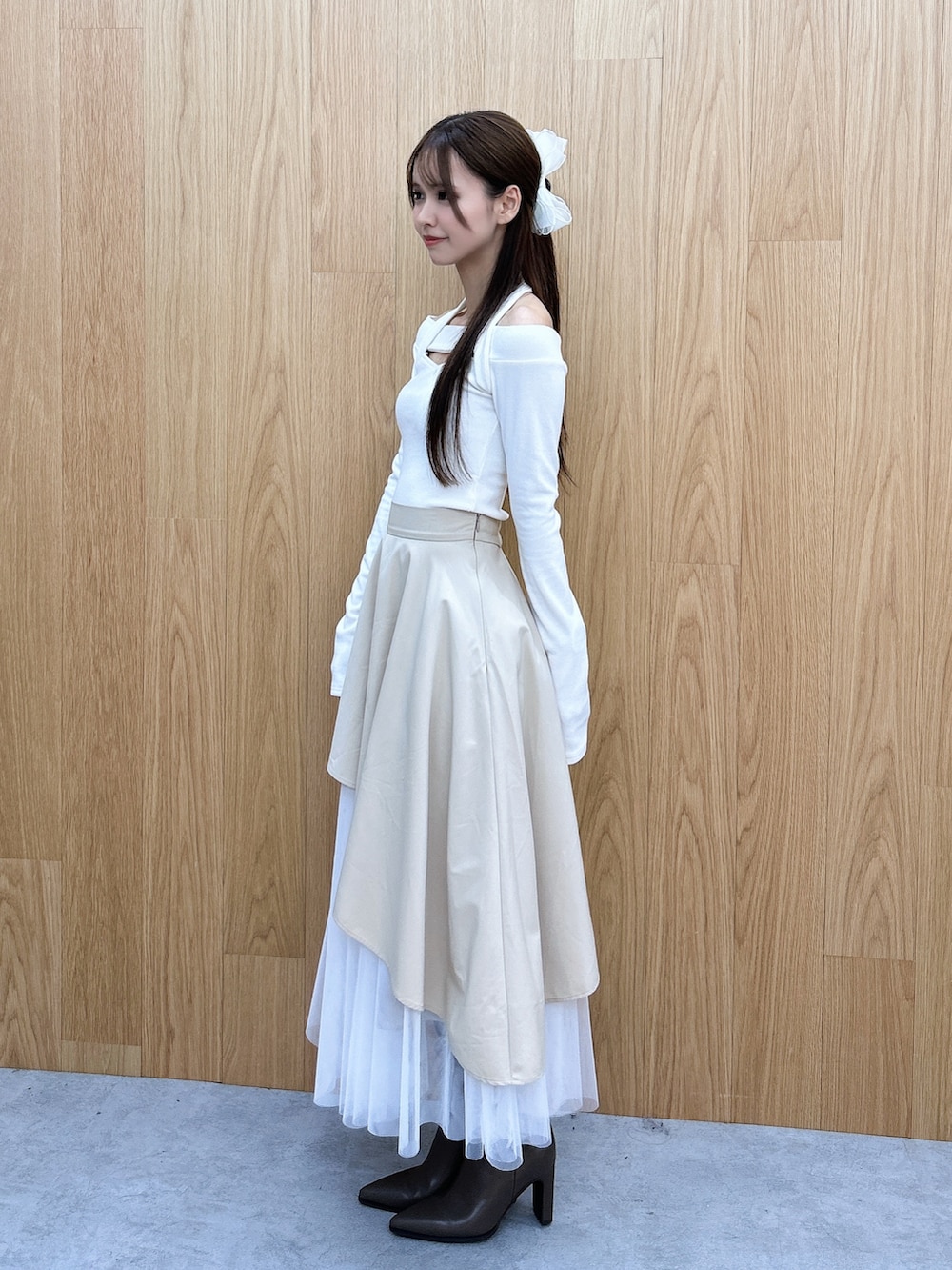 ベージュ系のスカート、ホワイト系のTシャツ/カットソー、ブラウン系のブーツを着用したレディースの秋コーディネートの3枚目の写真
