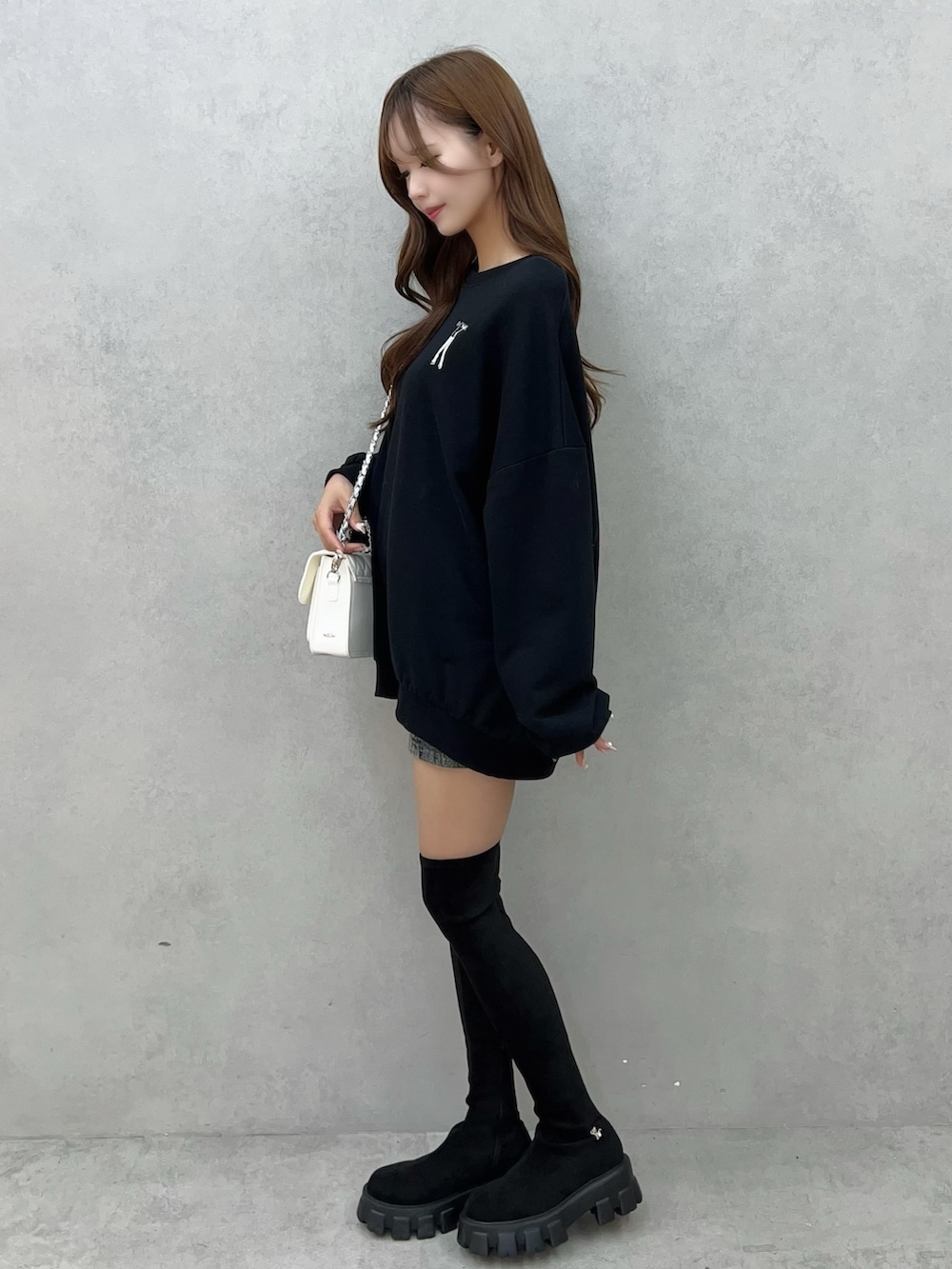 ブラック系のスウェット、ブルー系のデニムスカート、ホワイト系のショルダーバッグを着用したレディースの秋コーディネートの3枚目の写真