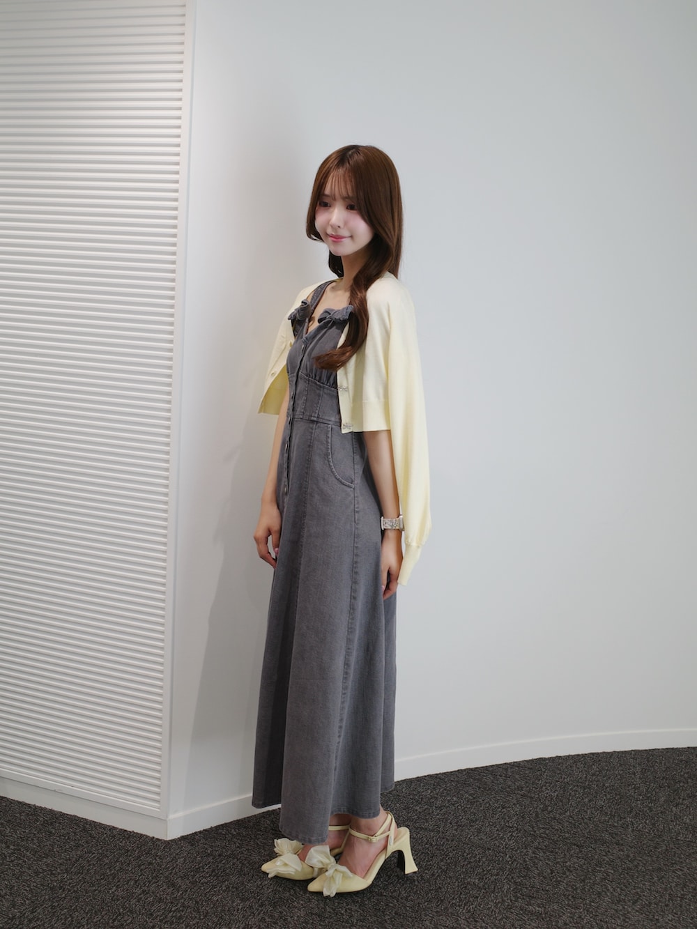 ブラック系のワンピース、イエロー系のパンプス、イエロー系のニット/セーターを着用したレディースの夏コーディネートの2枚目の写真