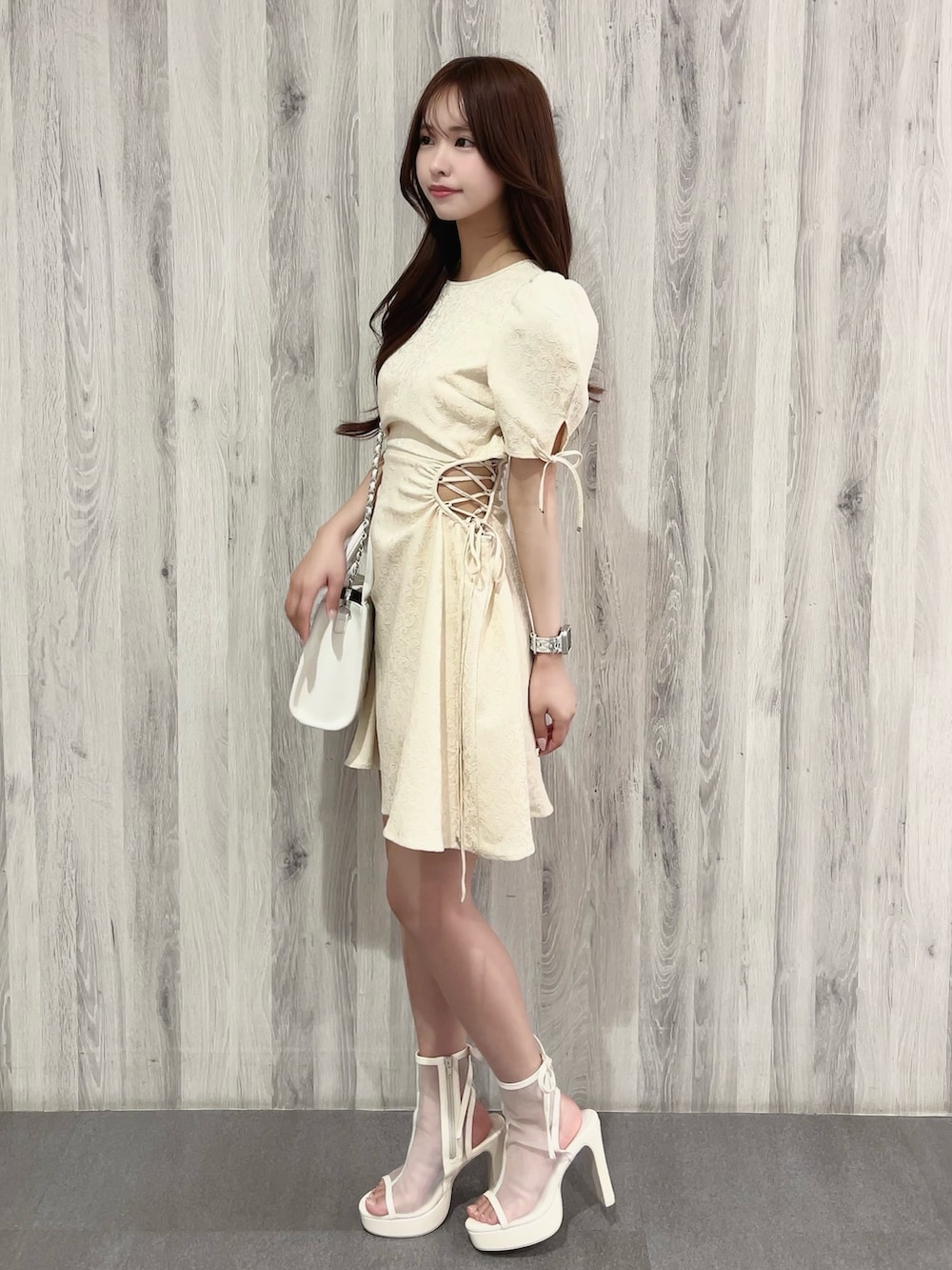 ホワイト系のワンピース、ホワイト系のサンダル、ホワイト系のハンドバッグを着用したレディースの春コーディネートの2枚目の写真