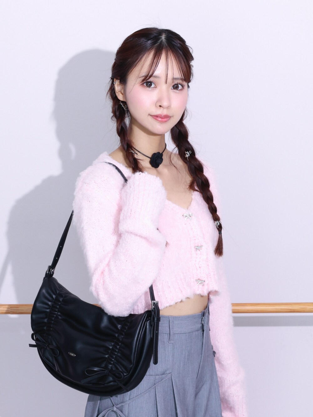 ブラック系のショルダーバッグ、ピンク系のカーディガン/ボレロ、グレー系のその他パンツを着用したレディースの冬コーディネートの2枚目の写真