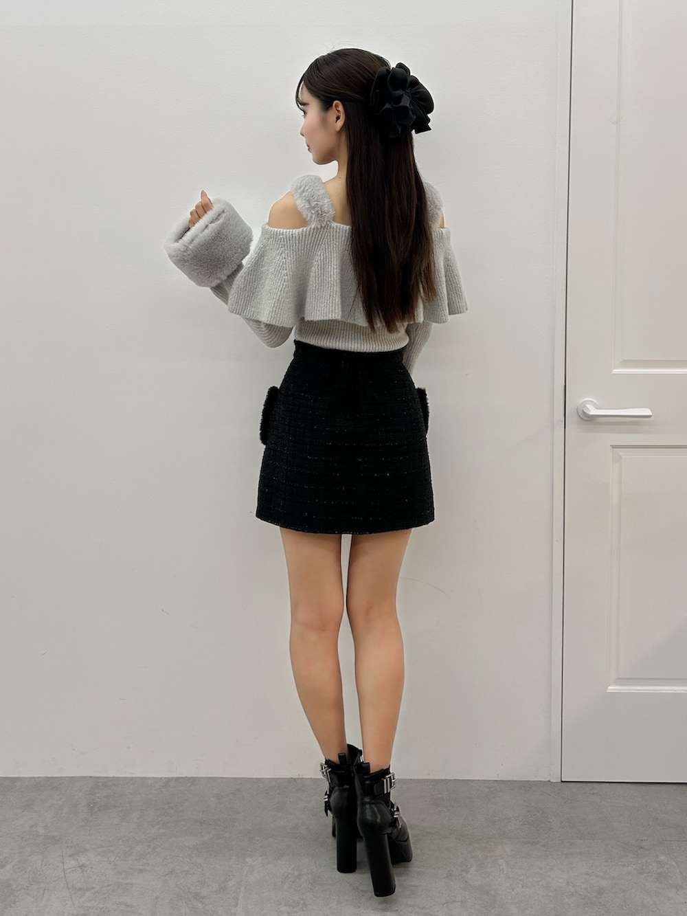 グレー系のニット/セーター、ブラック系のスカート、ブラック系のブーツを着用したレディースの秋コーディネートの3枚目の写真