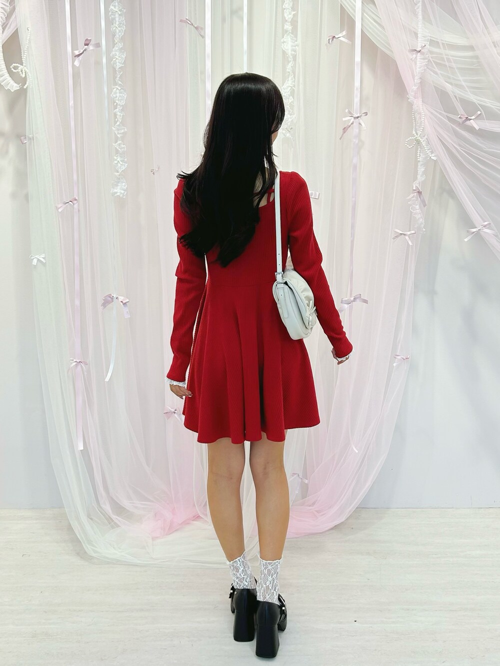 レッド系のワンピース、ホワイト系のショルダーバッグ、ブラック系のパンプスを着用したレディースの冬コーディネートの3枚目の写真