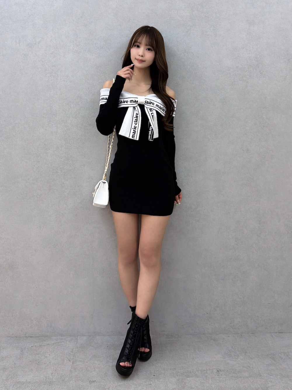 ブラック系のワンピース、ブラック系のサンダル、ホワイト系のハンドバッグを着用したレディースの冬コーディネートの2枚目の写真