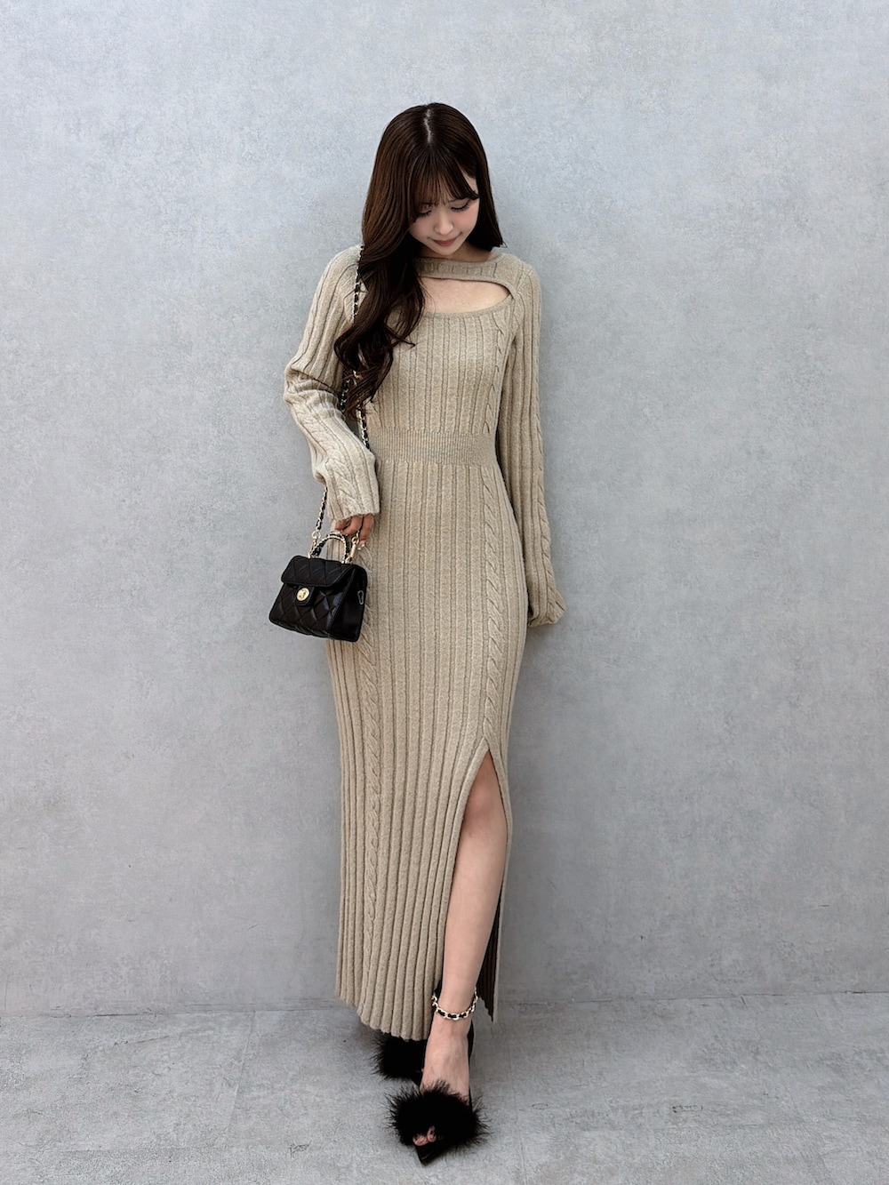 ベージュ系のワンピース、ブラック系のハンドバッグ、ブラック系のサンダルを着用したレディースの冬コーディネートの2枚目の写真