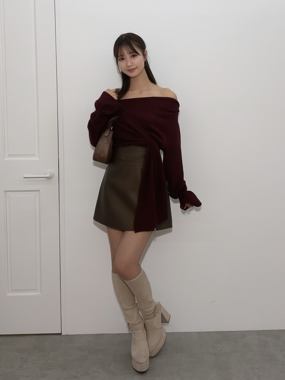 レッド系のTシャツ/カットソー、ブラウン系のスカート、ブラック系のブーツを着用したレディースの冬コーディネートの2枚目の写真