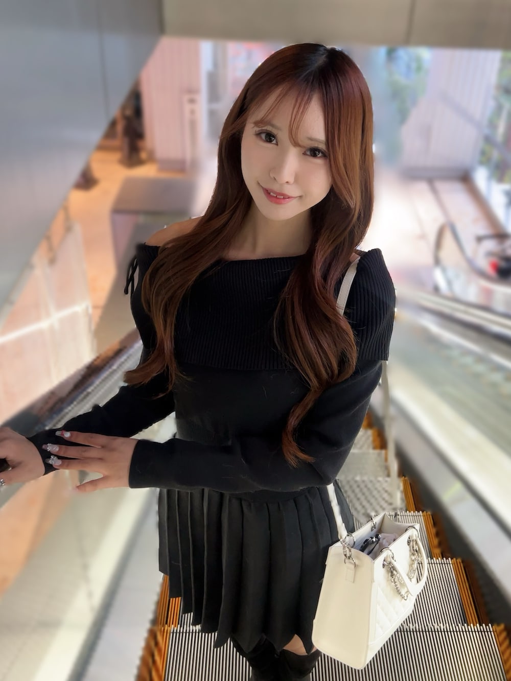 ブラック系のワンピース、ホワイト系のハンドバッグ、ブラック系のブーツを着用したレディースの冬コーディネートの5枚目の写真