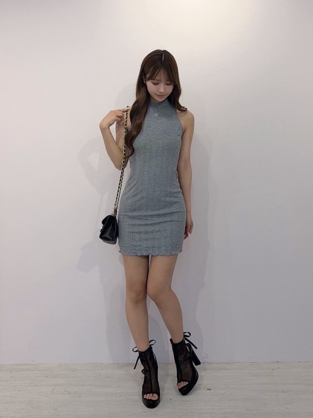 グレー系のワンピース、ブラック系のサンダル、ブラック系のハンドバッグを着用したレディースの夏コーディネートの2枚目の写真