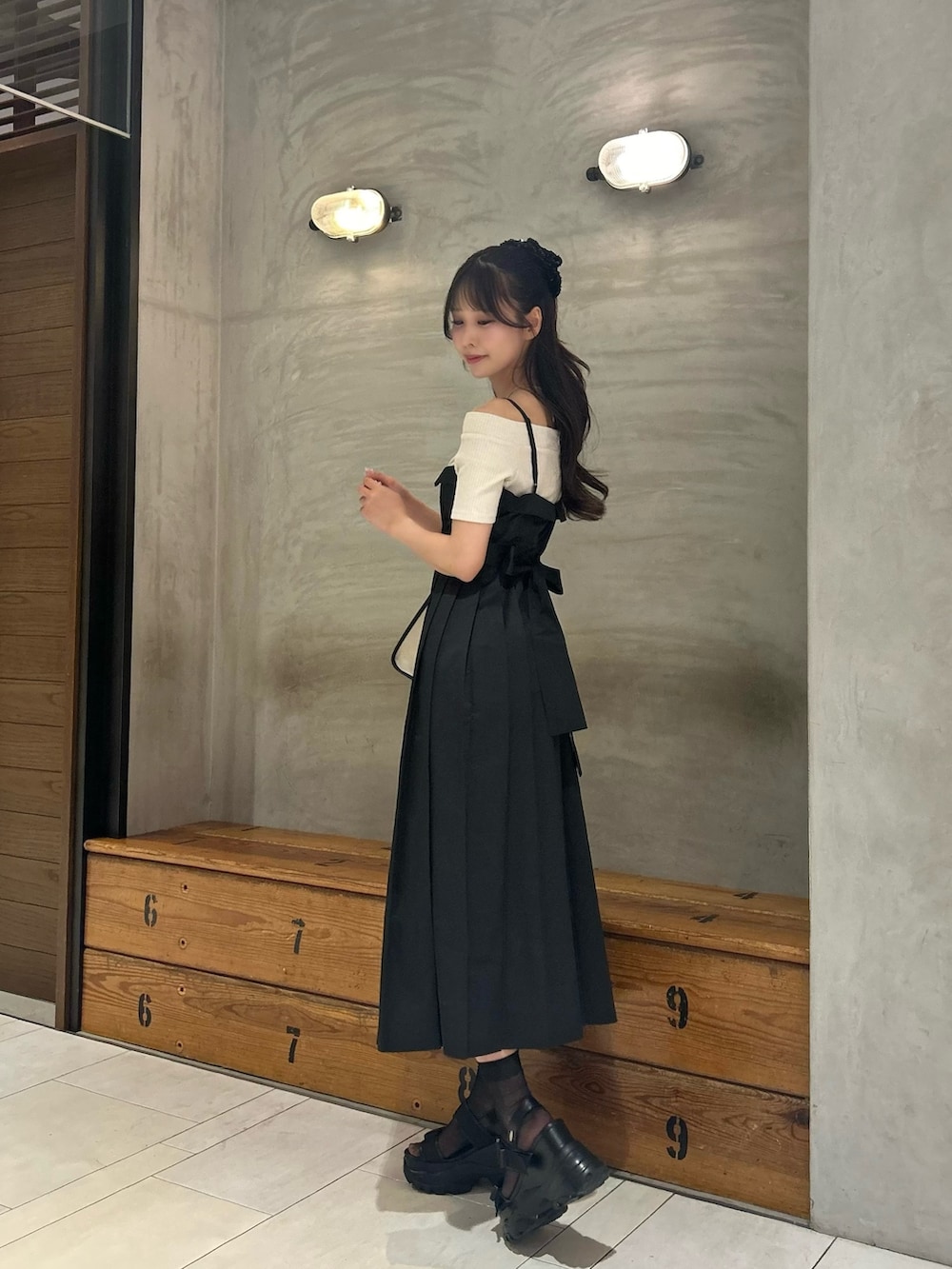 ブラック系のワンピース、ホワイト系のショルダーバッグ、ブラック系のサンダルを着用したレディースの春コーディネートの2枚目の写真