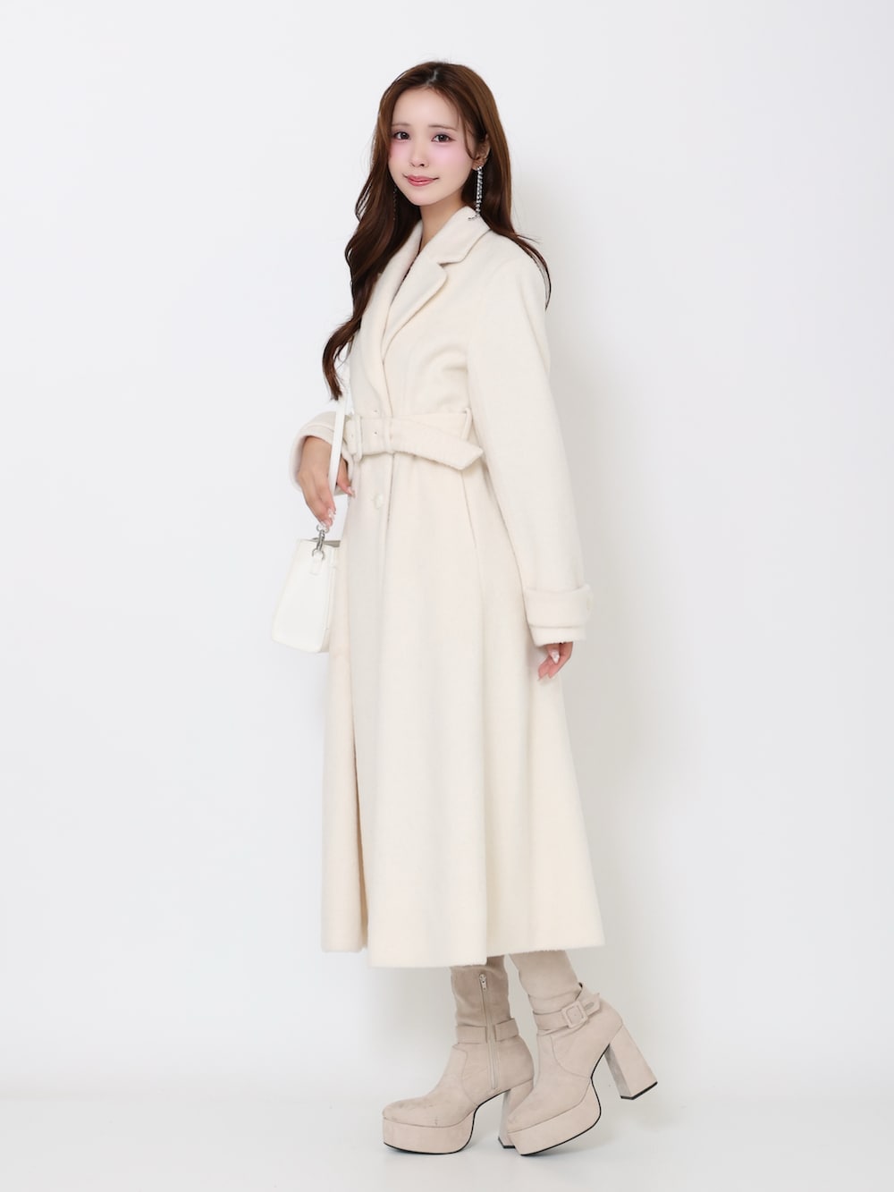 ホワイト系のその他アウター、ホワイト系のブーツ、ホワイト系のハンドバッグを着用したレディースの冬コーディネートの3枚目の写真