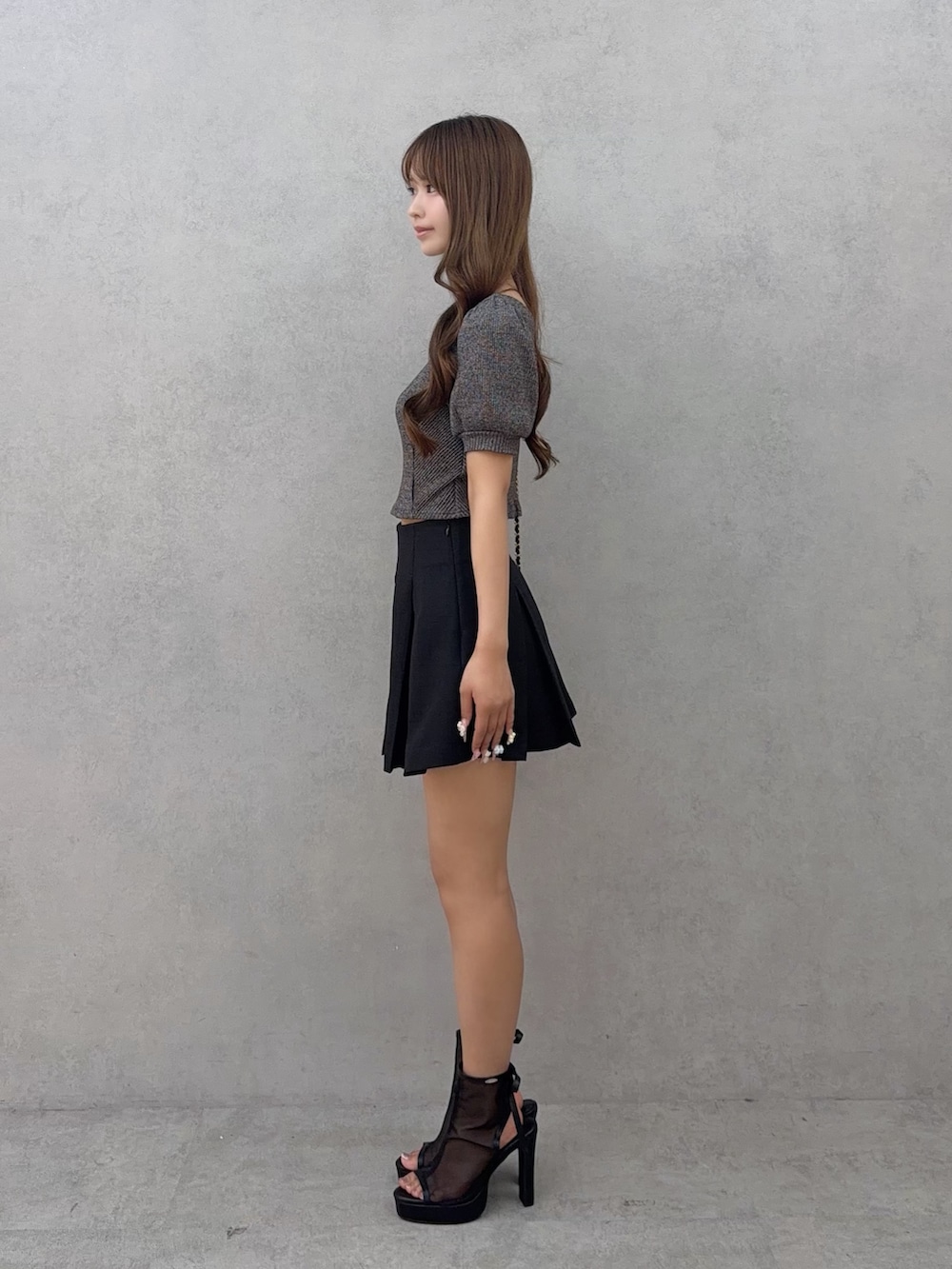ブラック系のスカート、グレー系のTシャツ/カットソー、ブラック系のサンダルを着用したレディースの夏コーディネートの3枚目の写真