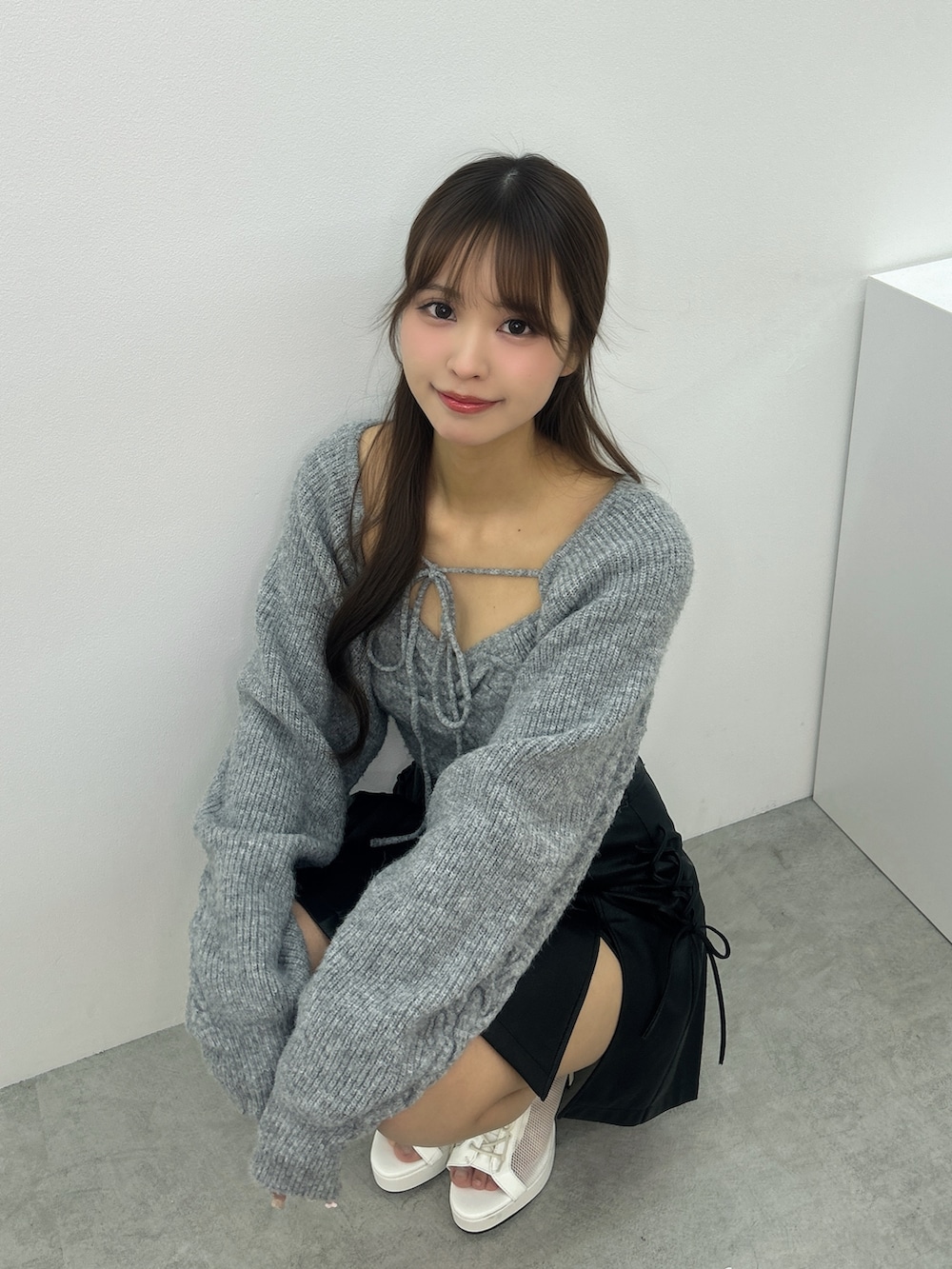 グレー系のニット/セーター、ブラック系のスカート、ホワイト系のブーツを着用したレディースの冬コーディネートの5枚目の写真