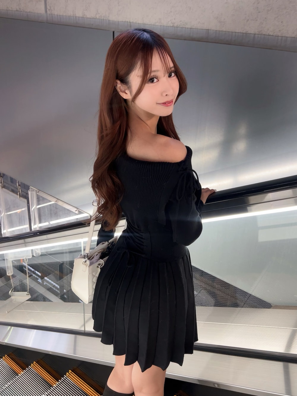 ブラック系のワンピース、ホワイト系のハンドバッグ、ブラック系のブーツを着用したレディースの冬コーディネートの6枚目の写真