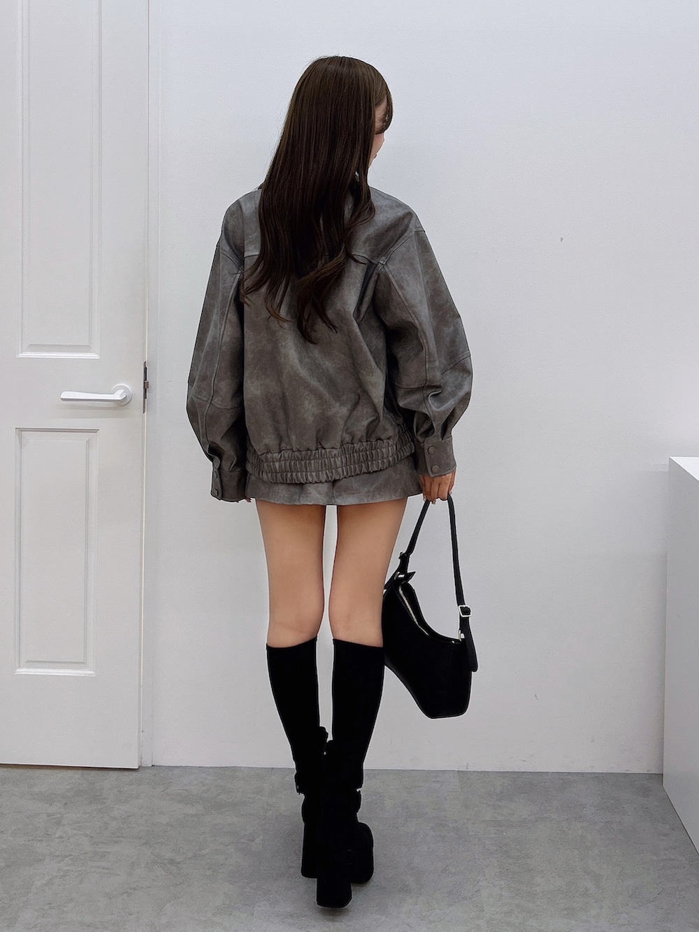 グレー系のスカート、グレー系のブルゾン、ホワイト系のニット/セーターを着用したレディースの秋コーディネートの3枚目の写真