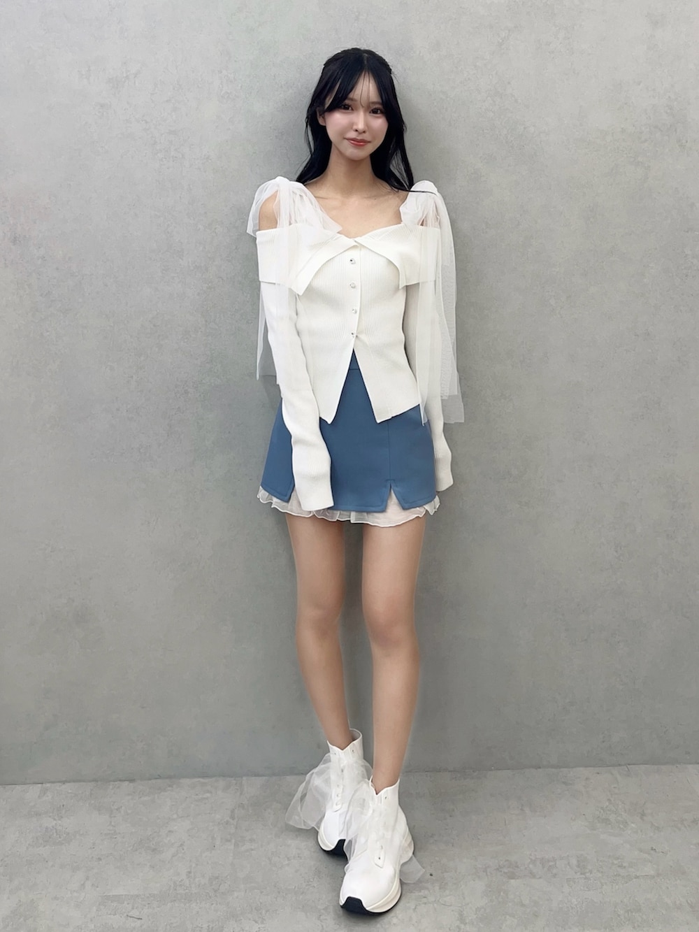 ホワイト系のニット/セーター、ブルー系のスカート、ホワイト系のブーツを着用したレディースの冬コーディネートの2枚目の写真