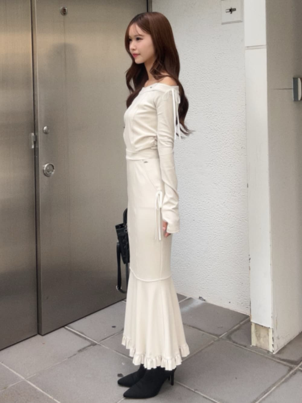 ホワイト系のTシャツ/カットソー、ホワイト系のスカート、ブラック系のハンドバッグを着用したレディースの秋コーディネートの2枚目の写真