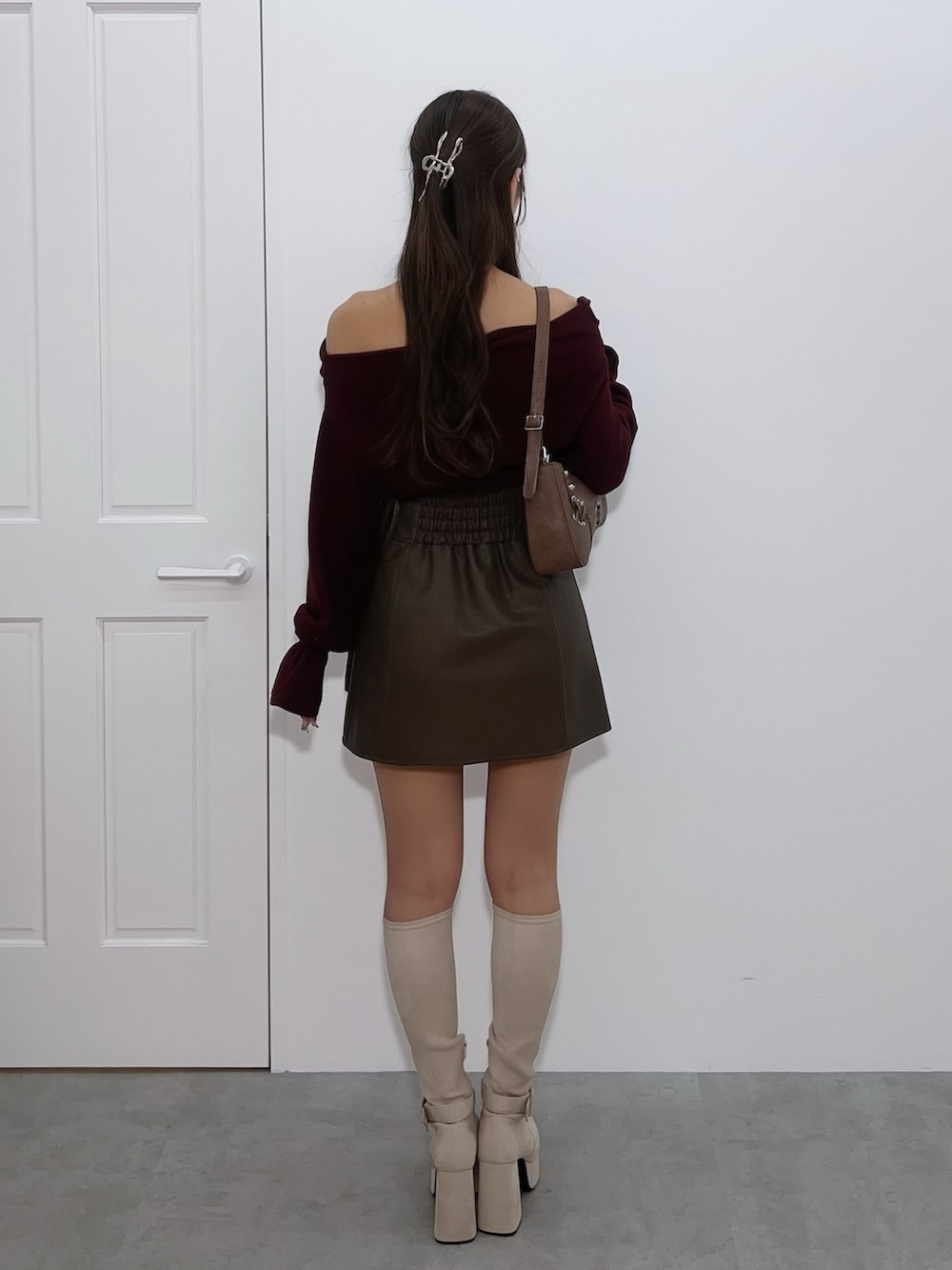 レッド系のTシャツ/カットソー、ブラウン系のスカート、ブラック系のブーツを着用したレディースの冬コーディネートの4枚目の写真