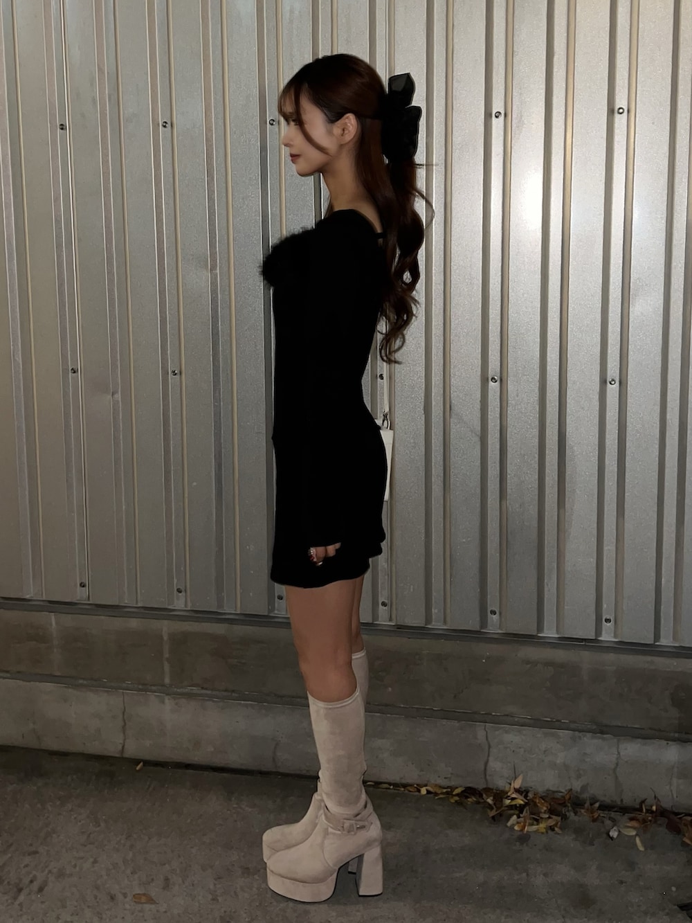 ブラック系のワンピース、ホワイト系のハンドバッグ、ホワイト系のブーツを着用したレディースの冬コーディネートの3枚目の写真