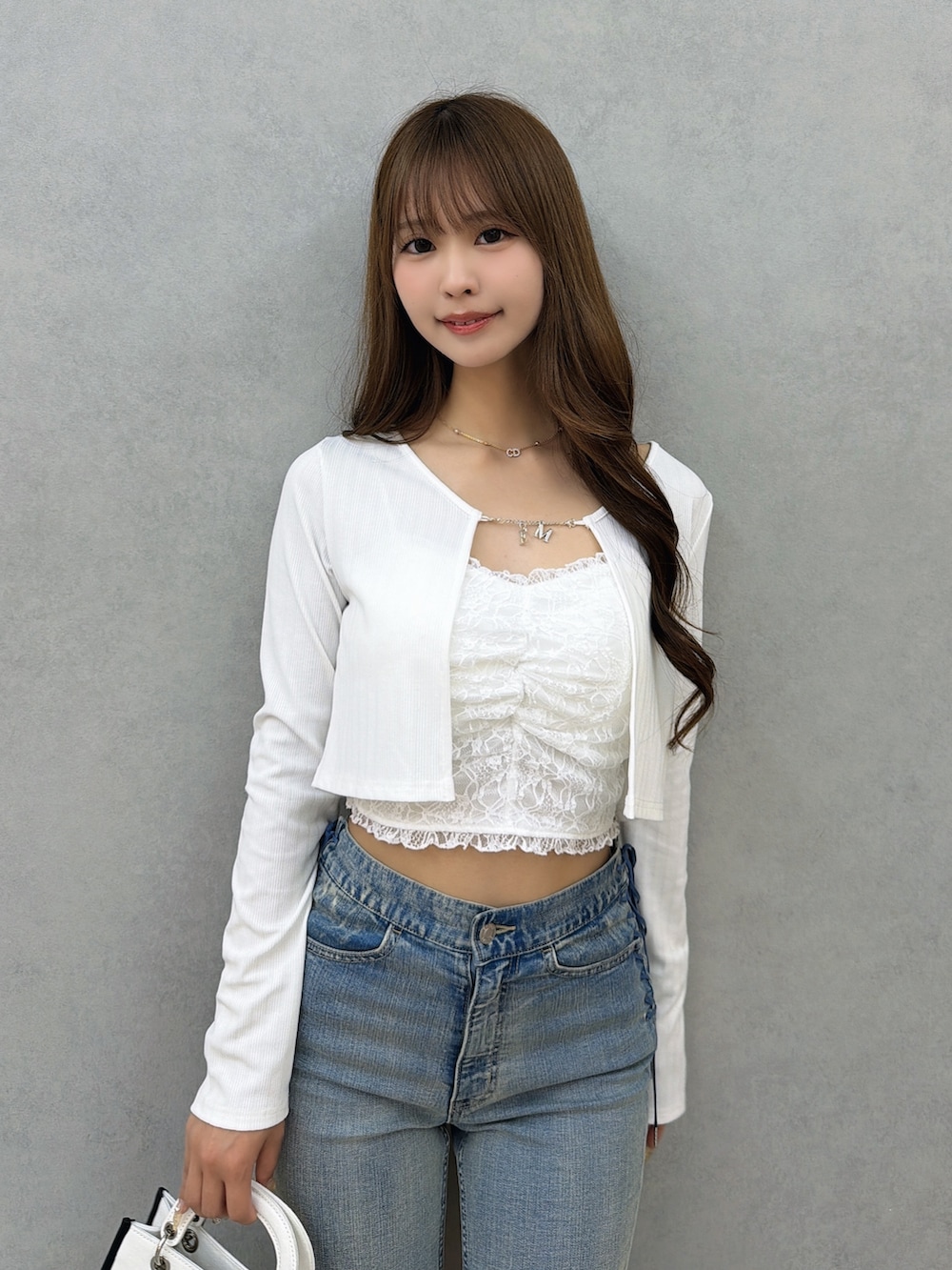 ブルー系のデニムパンツ、ホワイト系のサンダル、ホワイト系のショルダーバッグを着用したレディースの春コーディネートの5枚目の写真