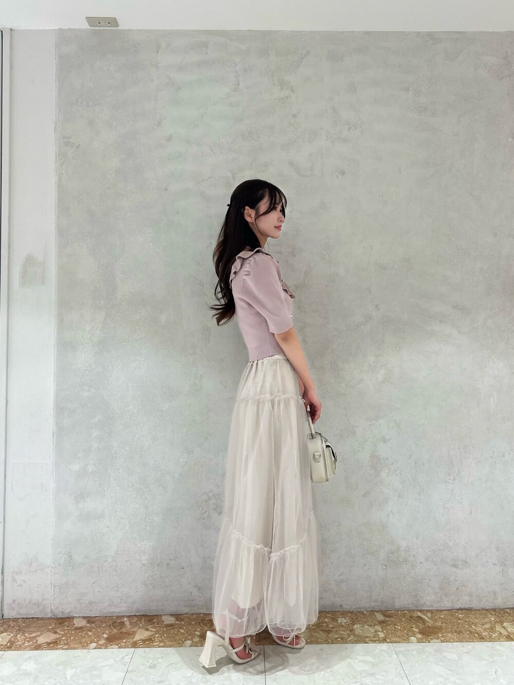 ピンク系のニット/セーター、ホワイト系のサンダル、ベージュ系のスカートを着用したレディースの夏コーディネートの2枚目の写真