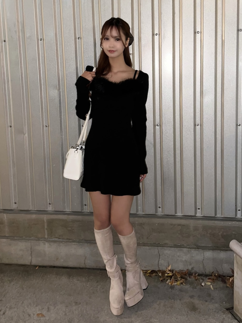 ブラック系のワンピース、ホワイト系のハンドバッグ、ホワイト系のブーツを着用したレディースの冬コーディネートの2枚目の写真