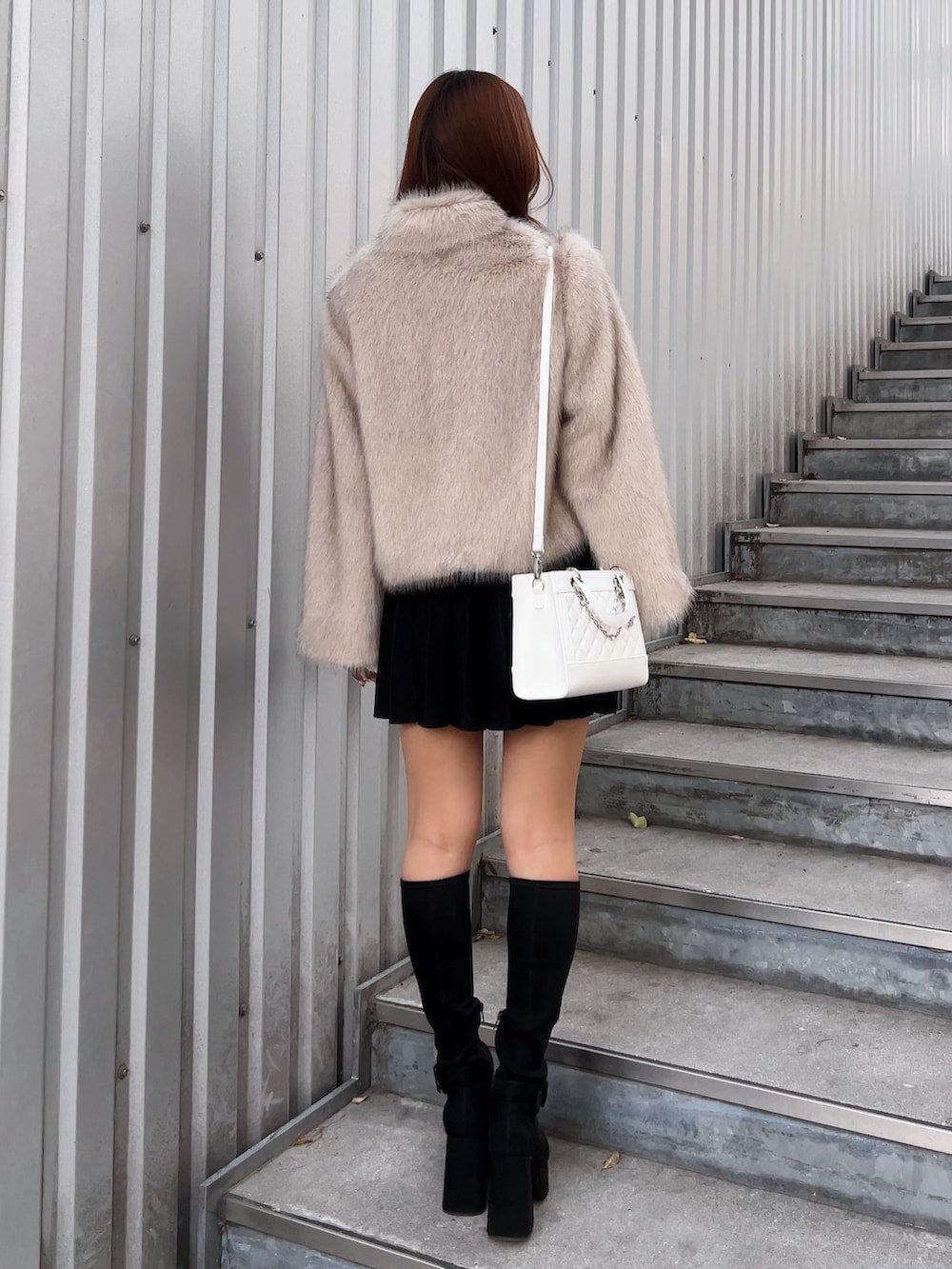 ベージュ系のブルゾン、ブラック系のワンピース、ブラック系のブーツを着用したレディースの冬コーディネートの4枚目の写真