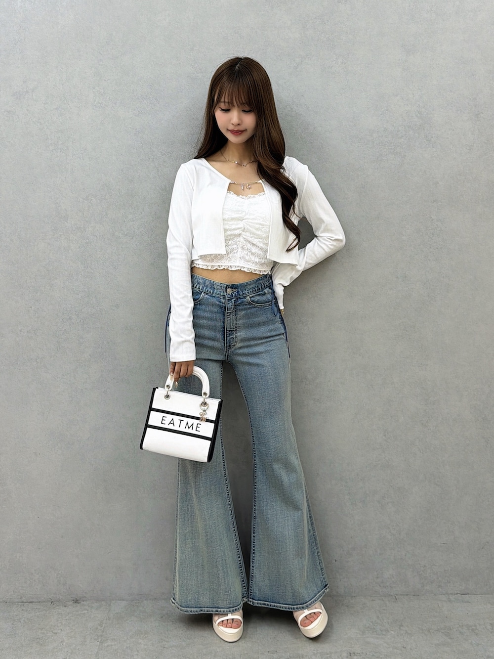 ブルー系のデニムパンツ、ホワイト系のサンダル、ホワイト系のショルダーバッグを着用したレディースの春コーディネートの2枚目の写真