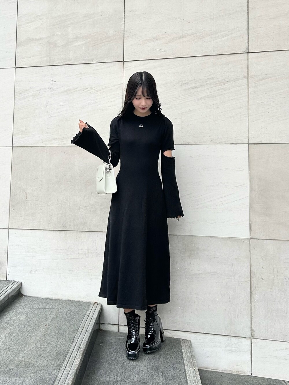 その他のブーツ、ブラック系のワンピース、ホワイト系のショルダーバッグを着用したレディースの冬コーディネートの2枚目の写真