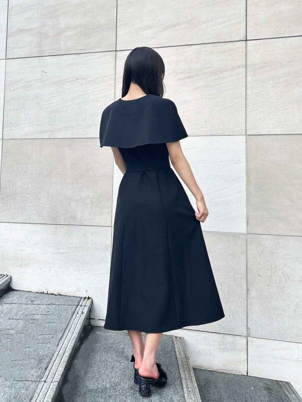 ホワイト系のショルダーバッグ、ブラック系のパンプス、ブラック系のワンピースを着用したレディースの夏コーディネートの2枚目の写真