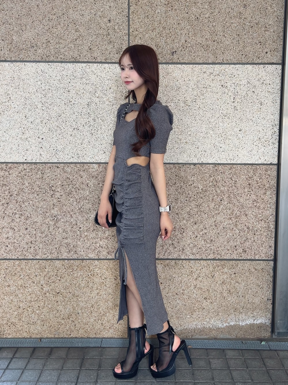 グレー系のワンピース、ブラック系のサンダル、ブラック系のハンドバッグを着用したレディースの春コーディネートの2枚目の写真