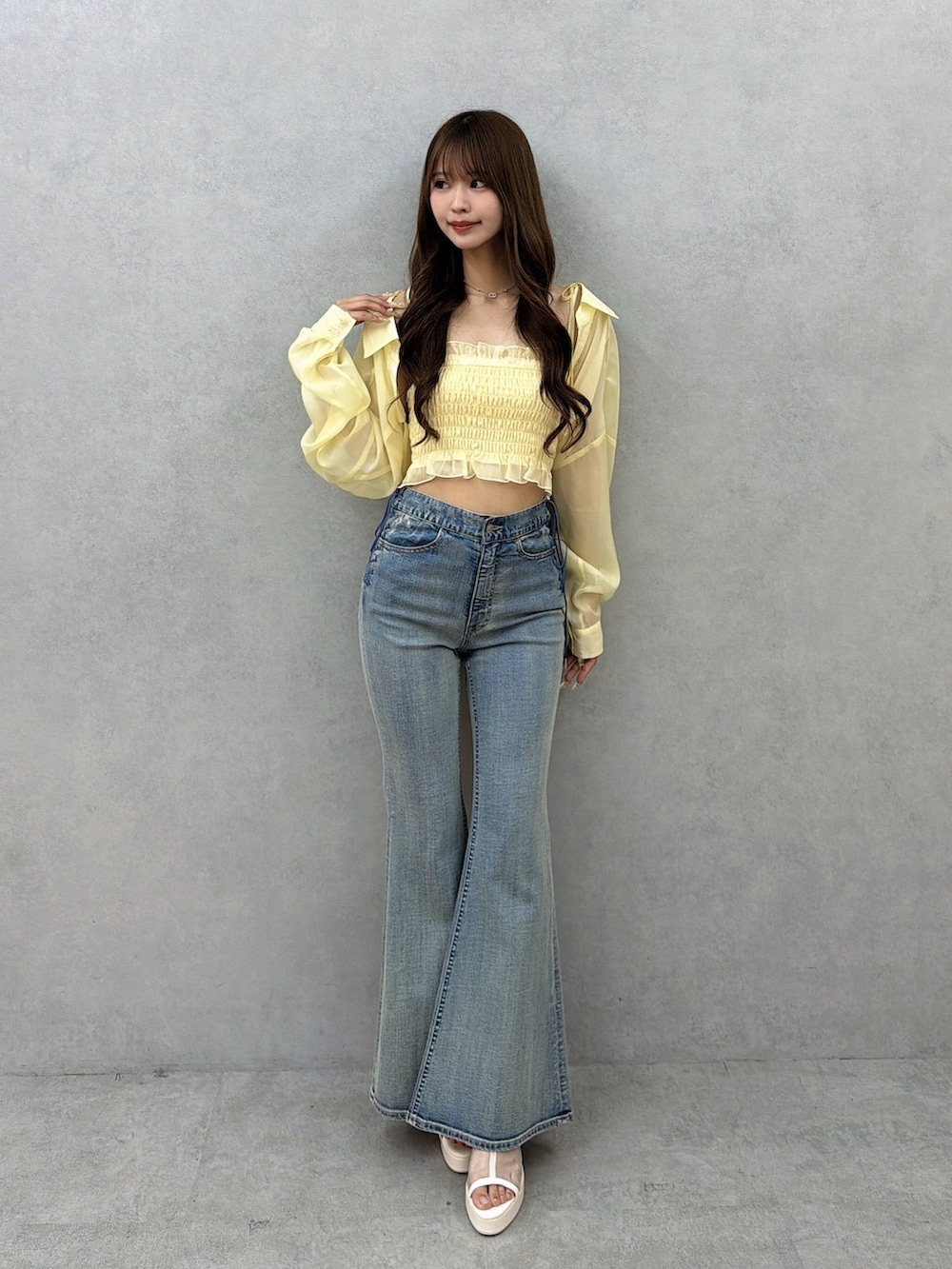 ブルー系のデニムパンツ、イエロー系のシャツ/ブラウス、ホワイト系のサンダルを着用したレディースの春コーディネートの2枚目の写真