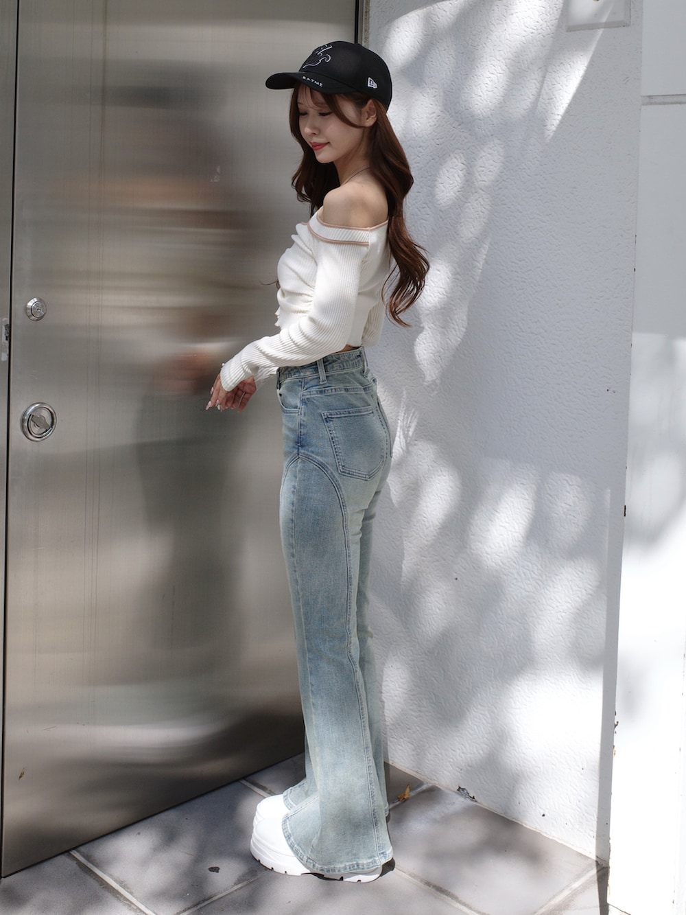 ブルー系のデニムパンツ、ホワイト系のTシャツ/カットソー、ブラック系のキャップを着用したレディースの冬コーディネートの3枚目の写真