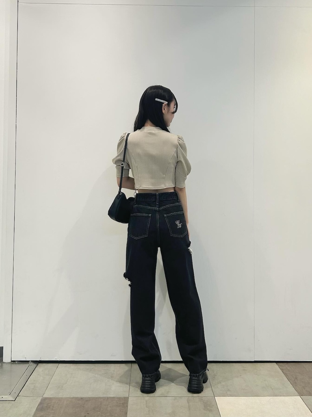 ブラック系のデニムパンツ、ブラック系のショルダーバッグ、ブラック系のサンダルを着用したレディースの春コーディネートの2枚目の写真