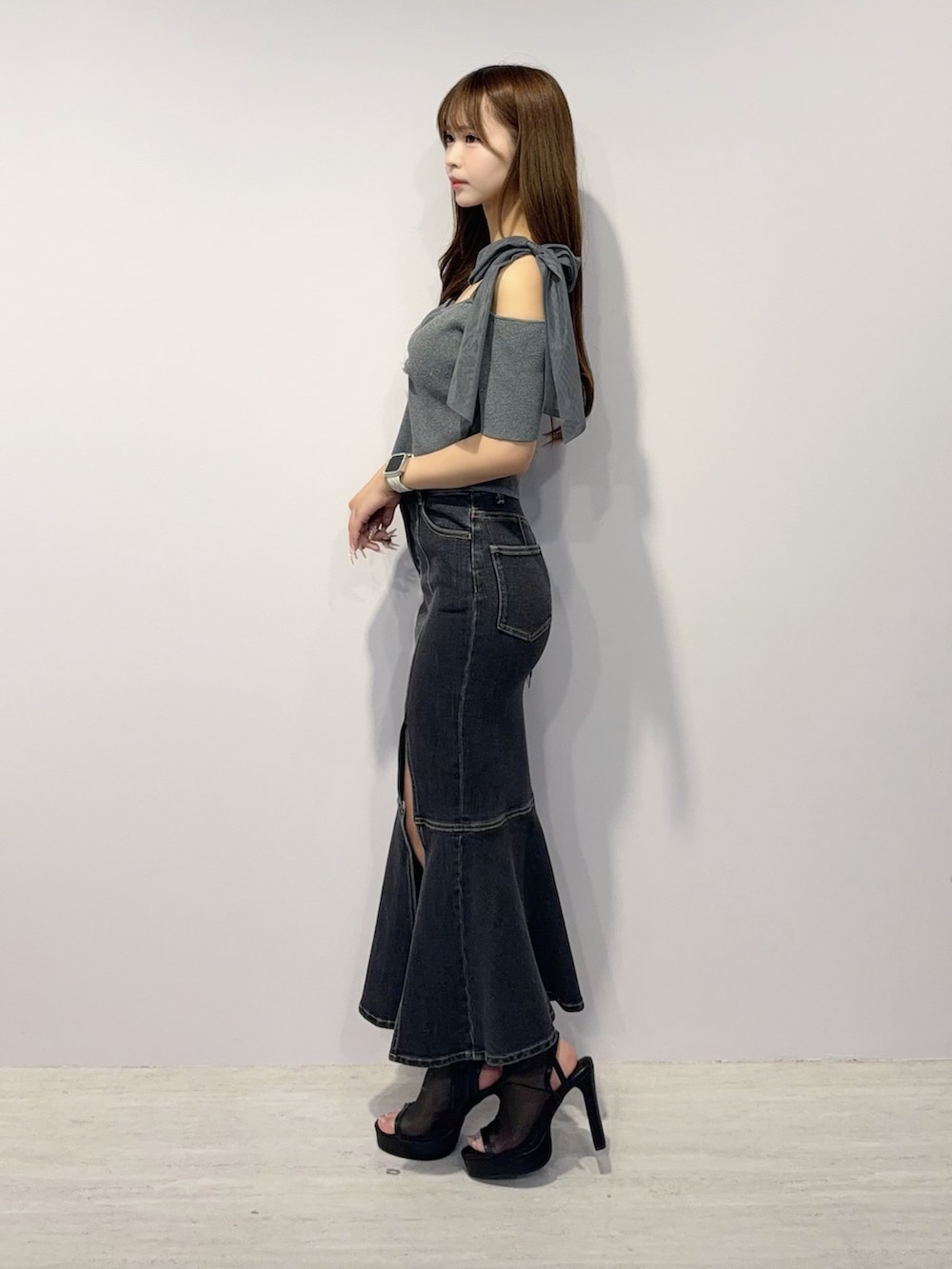 ブラック系のデニムスカート、グレー系のTシャツ/カットソー、ブラック系のサンダルを着用したレディースの春コーディネートの3枚目の写真